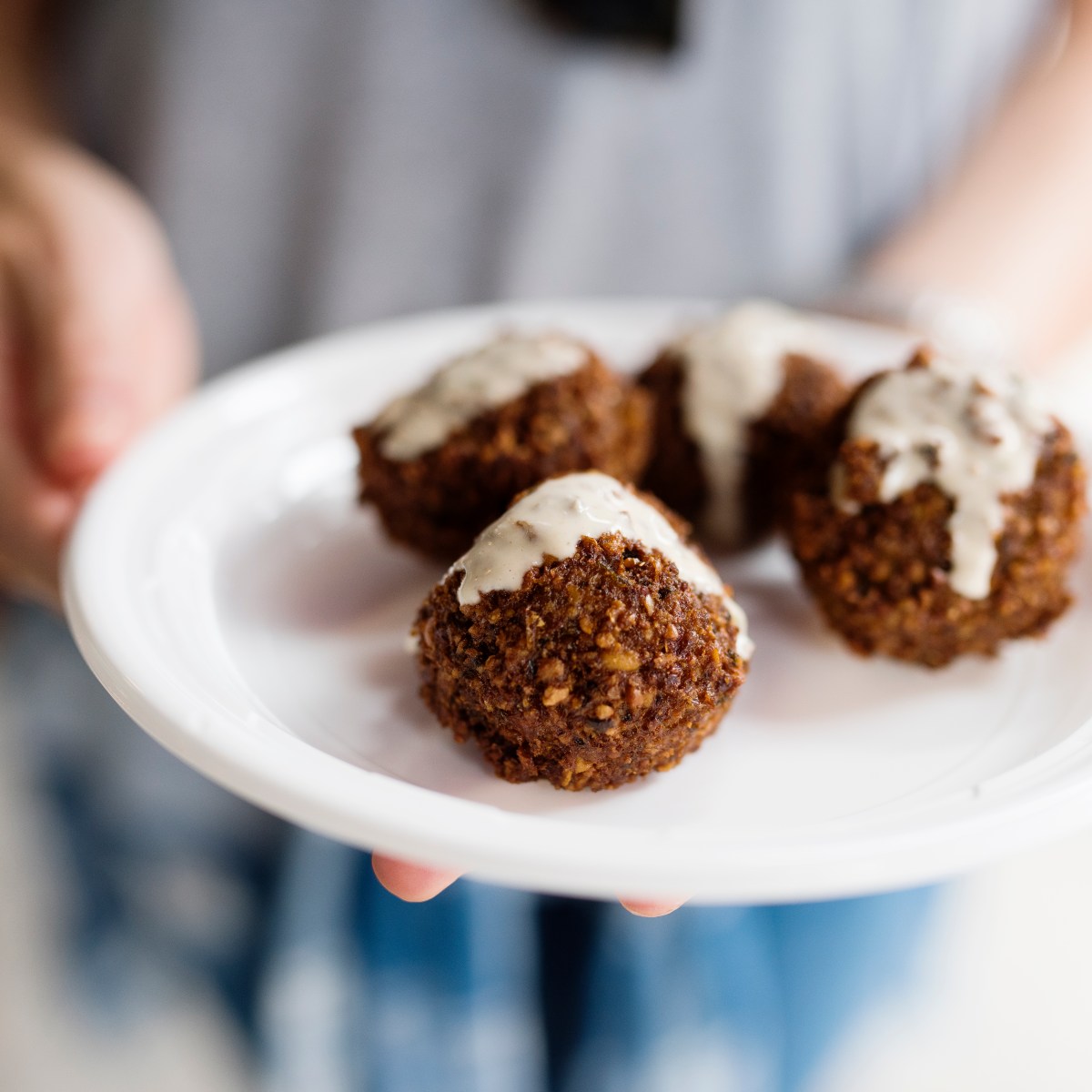 Plate of crispy falafel with fresh vegetables, pita, and tahini sauce served at a local Brooklyn Middle Eastern restaurant.