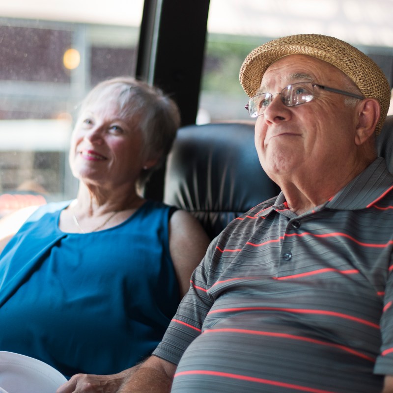 older couple sitting on bus smiling